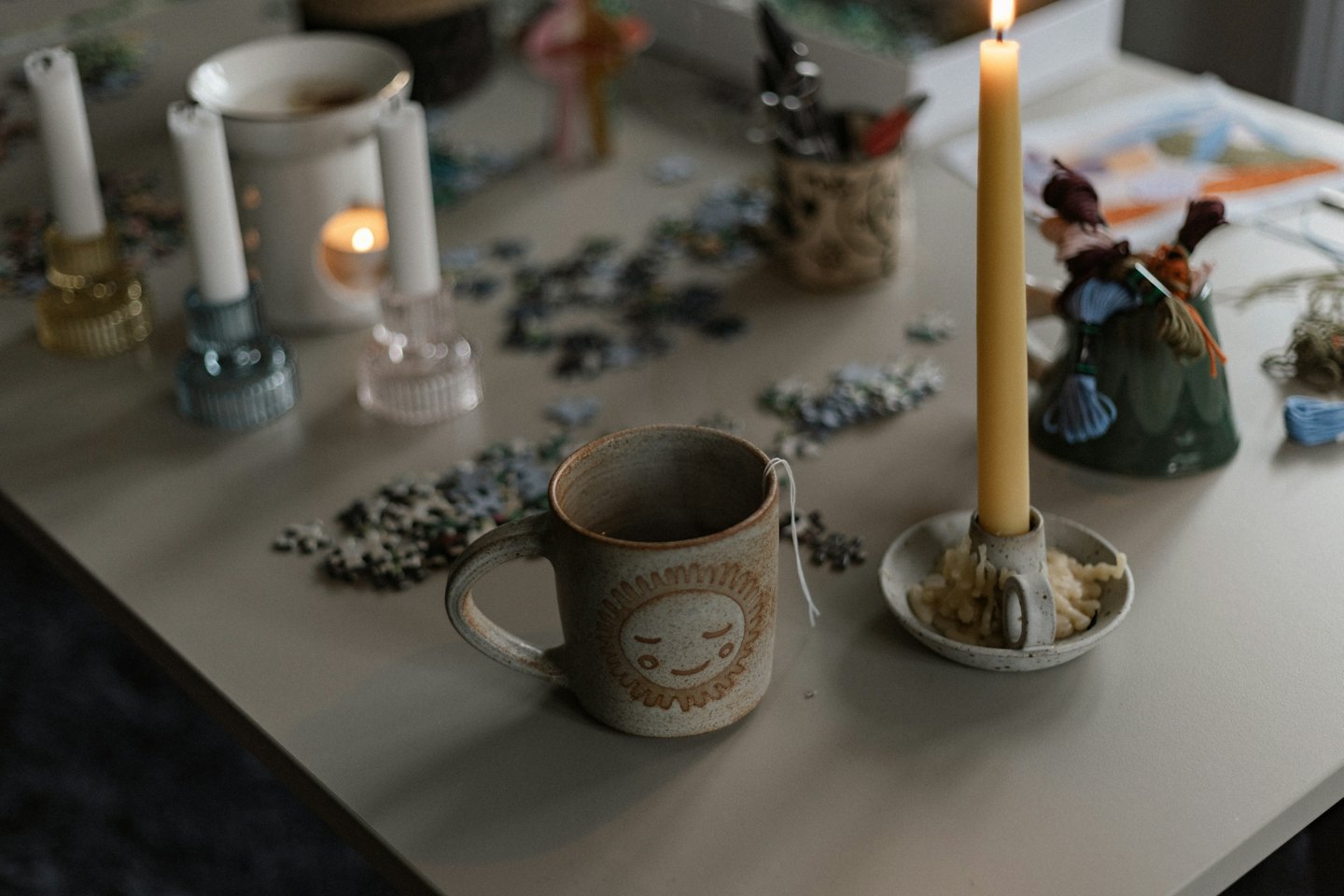 A mug with a sun design sits beside scattered puzzle pieces.